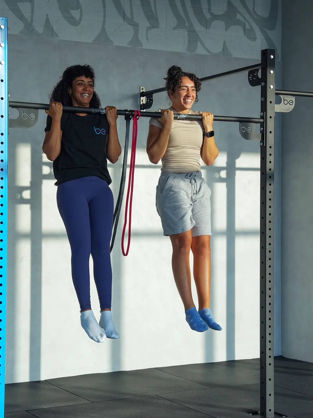 Two members laughing while hanging from the bar